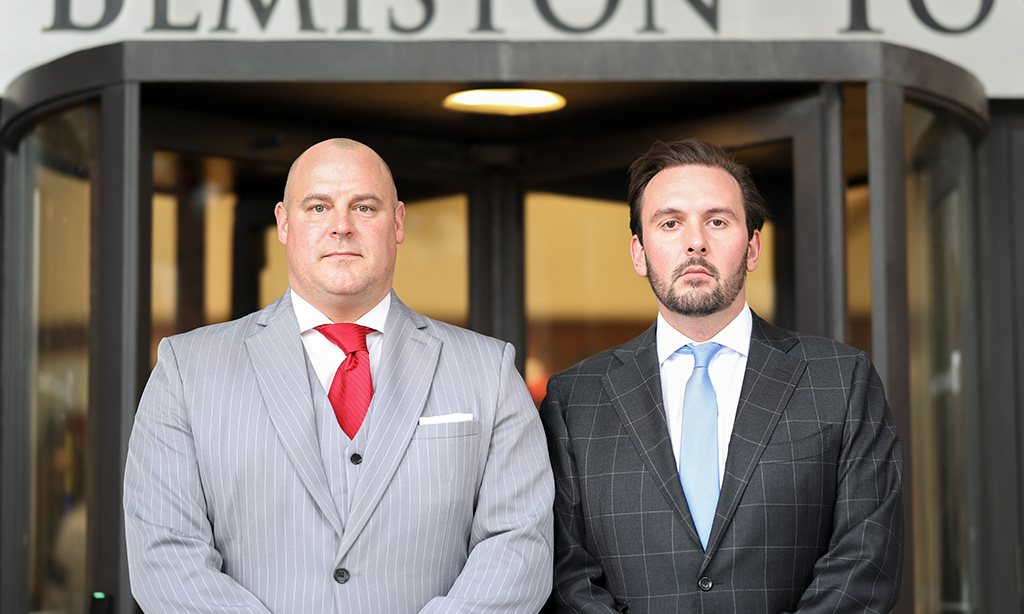 Chris Combs and Steve Waterkotte of Combs Waterkotte standing shoulder-to-shoulder outside a court building.